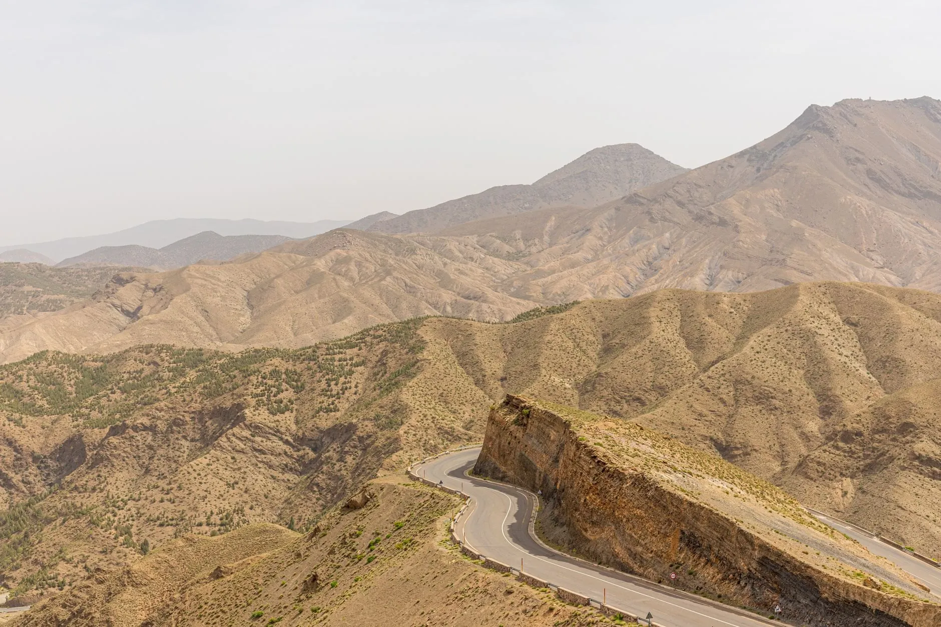A road switching back across dry, folded mountainsides in the High Atlas