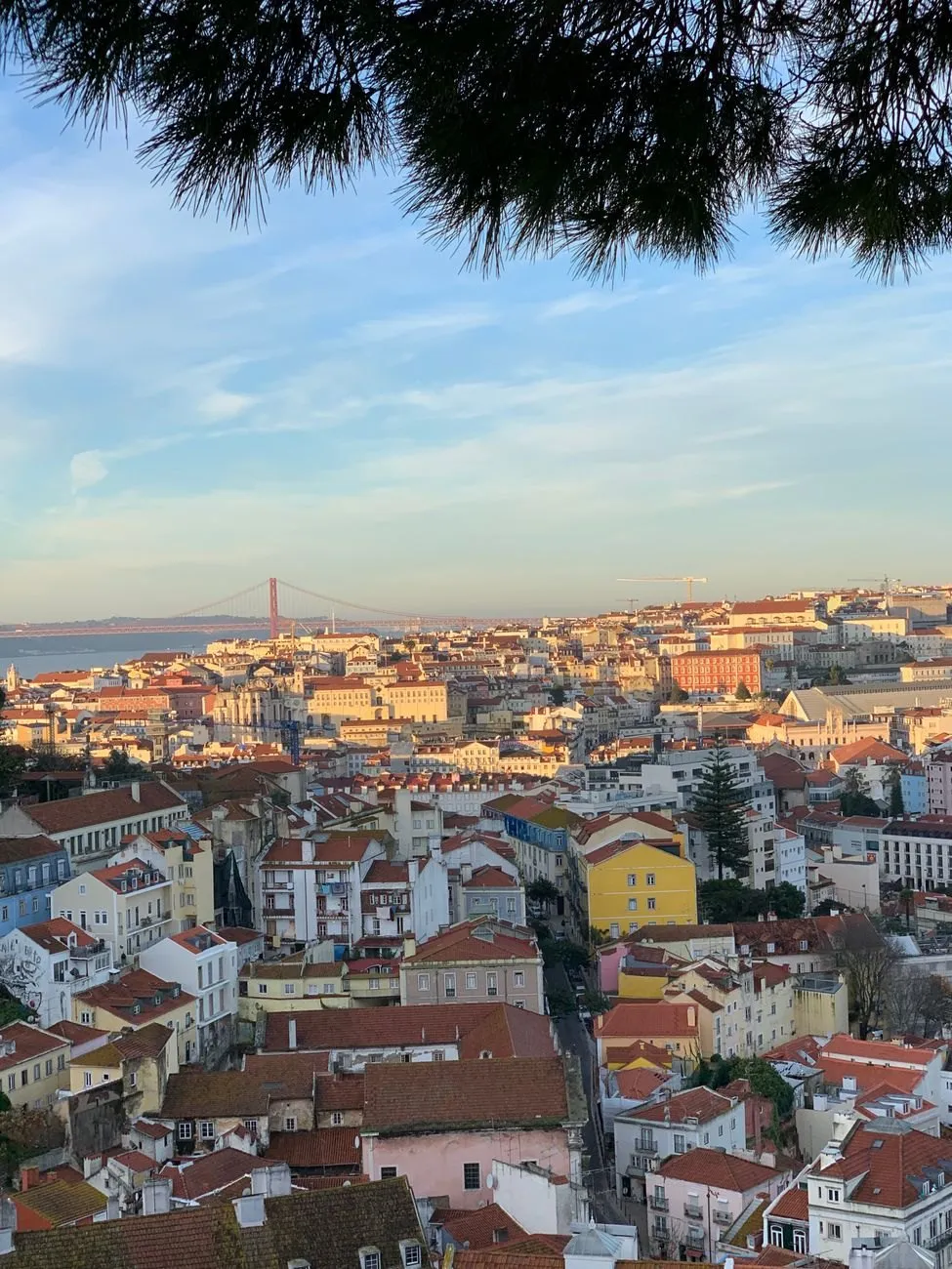 The view from a Lisbon miradouro over tiled roofs to the river and the suspension bridge